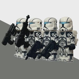 May include: Four white and gray action figures with black weapons. The figures wear white helmets with blue visors and black markings. The figures are standing in a row, each holding a black weapon.