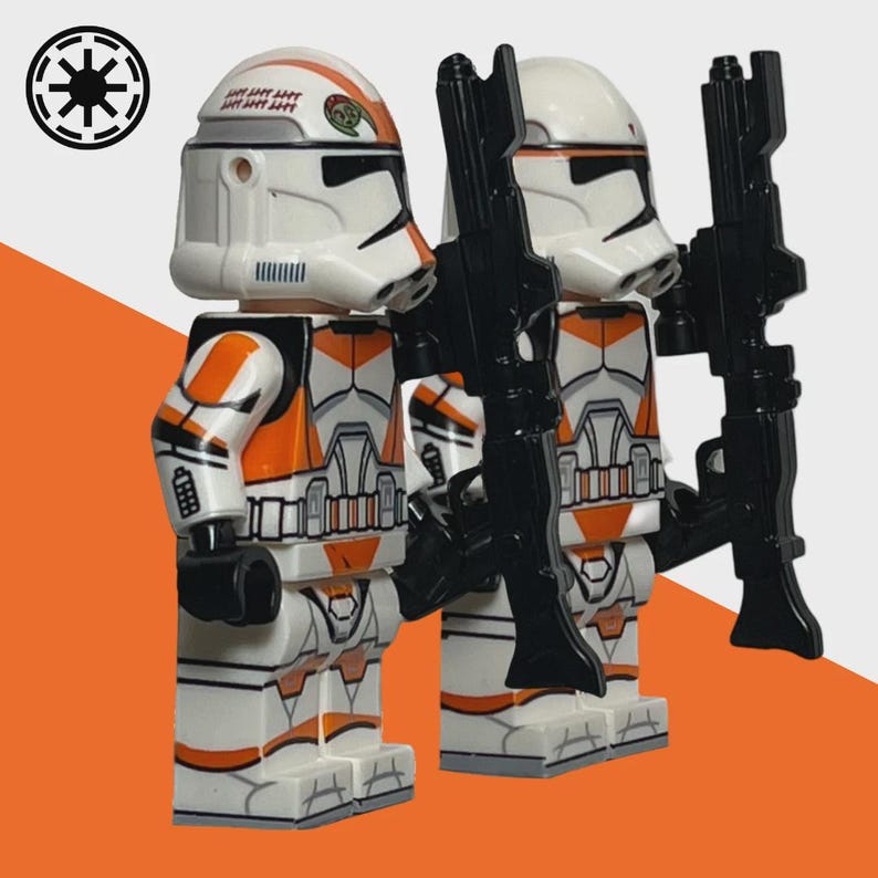 May include: Two white and orange toy figures with black rifles. The figures have helmets and armor with orange accents. The background is white and orange, with a black and white symbol in the upper left corner.