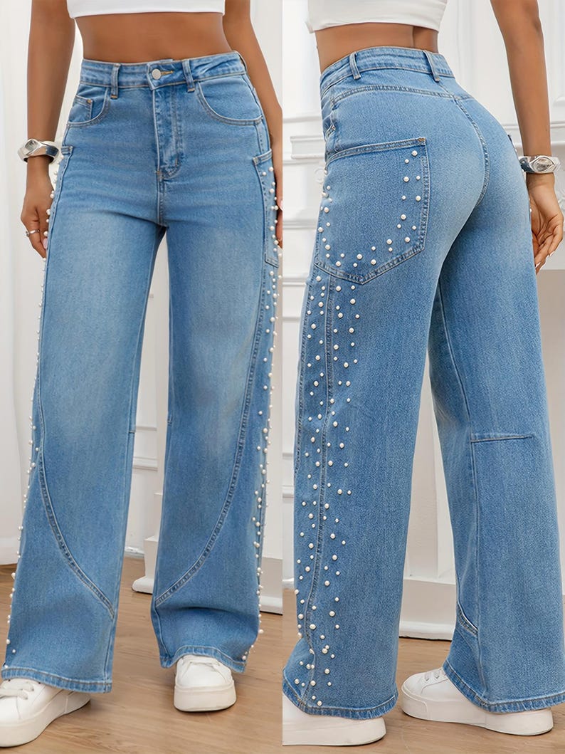 May include: Light blue denim jeans with a wide leg design. The jeans feature white pearl embellishments along the side seams and back pockets. The jeans have a classic five-pocket design and a button and zipper closure.