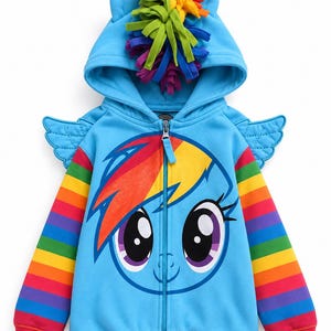 May include: A bright blue zip-up hoodie featuring a large graphic of a cartoon character face with a rainbow mane. The hood includes felt ears and a multi-colored fringe crest. The sleeves have horizontal rainbow stripes and small blue wings.