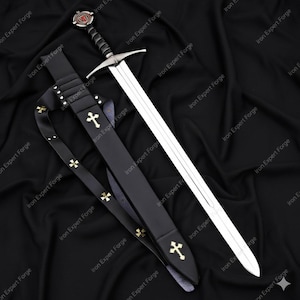 May include: A medieval sword with a silver blade and a black handle, resting in a black leather sheath. The sheath and strap are adorned with gold crosses. The sword's hilt features a red and silver design.