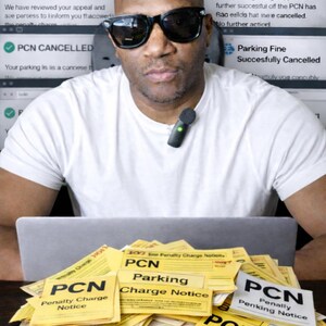 May include: A man wearing sunglasses and a white t-shirt is in front of a laptop and several computer screens. A pile of yellow PCN (Penalty Charge Notice) forms are in front of the laptop. The screens show parking fine appeal information.