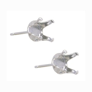 May include: Two silver-colored earring settings with a post and a four-prong design to hold a gemstone. The settings are made of a shiny, metallic material and are displayed against a white background.