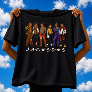 Może przedstawiać: Czarna koszulka z kreskówkową ilustracją sześciu mężczyzn w kolorowych strojach. Słowo "JACKSONS" jest wydrukowane na biało, w stylu serialu telewizyjnego "Friends". Tło to błękitne niebo z białymi chmurami.