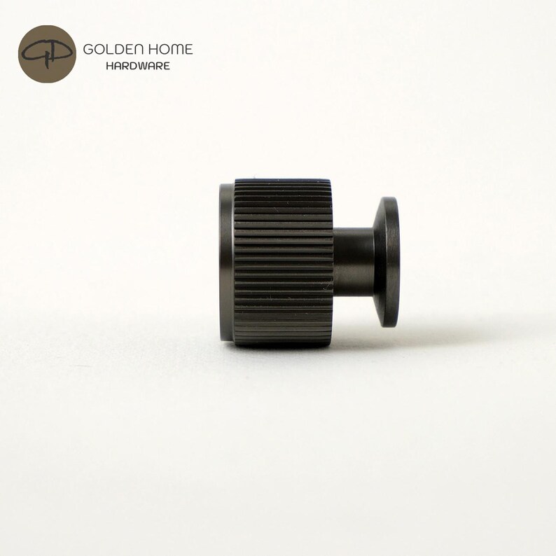 May include: A dark gray metal cabinet knob with a ridged cylindrical body and a circular base. The knob is designed for furniture hardware. The logo "GOLDEN HOME HARDWARE" is in the upper left corner.