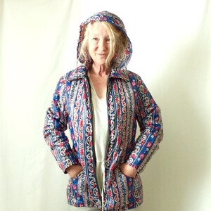 May include: A blue, red, and white patterned jacket with a hood. The jacket has a zipper closure and two pockets.
