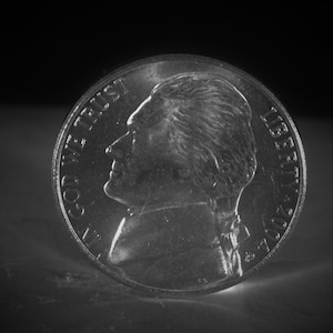 May include: A silver US nickel coin with the profile of Thomas Jefferson on one side and the words "In God We Trust" and "Liberty 2007" on the other side.