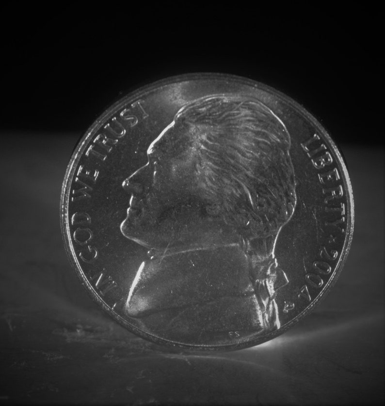 May include: A silver US nickel coin with the profile of Thomas Jefferson on one side and the words "In God We Trust" and "Liberty 2007" on the other side.