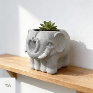 Puede incluir: Una taza de cerámica blanca con un asa negra y el texto "But First, Coffee" en negrita negra. La taza está llena de un líquido oscuro, probablemente café, y se encuentra sobre una superficie de color claro.