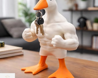 May include: A white and orange duck-shaped key holder with a muscular physique. The duck's beak holds a set of keys. The duck has orange feet and a matching beak. The key holder is a decorative and functional home decor item.