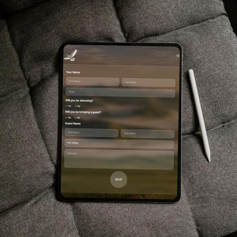 May include: A black tablet displaying an online form with fields for name, email, and RSVP. A white stylus rests beside the tablet on a gray, textured surface. The form includes the text "Your Name", "Email", "Will you be attending?", "Will you be bringing a guest?", "Guest Name", and "RSVP".