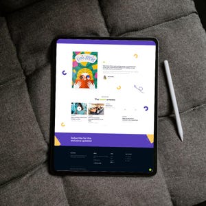 May include: A black tablet displaying a website with a colorful illustration of a person reading a book. A white stylus rests on the right. The website features articles and a subscription call to action.