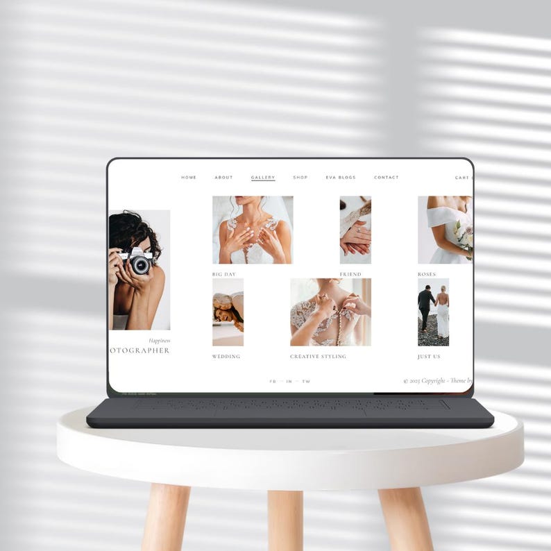 May include: A laptop on a white table shows a wedding website. The site's navigation includes "Home", "About", "Gallery", "Shop", "Eva Blogs", and "Contact". Images showcase a photographer, wedding dresses, and couples, with text like "Wedding" and "Creative Styling".