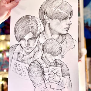 May include: A black and white pencil sketch print depicting a character in three poses, wearing an R.P.D. vest. The print includes the text "R.P.D." on the vest. The character is shown with short hair.