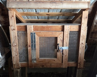 Könnte beinhalten: Ein Kaninchenstall aus Holz mit einem Metalldach, Drahtgitterseiten und einer Scharniertür. Der Stall steht auf Holzpfosten und hat einen Riegel zum Sichern der Tür. Die Struktur besteht aus Naturholz.