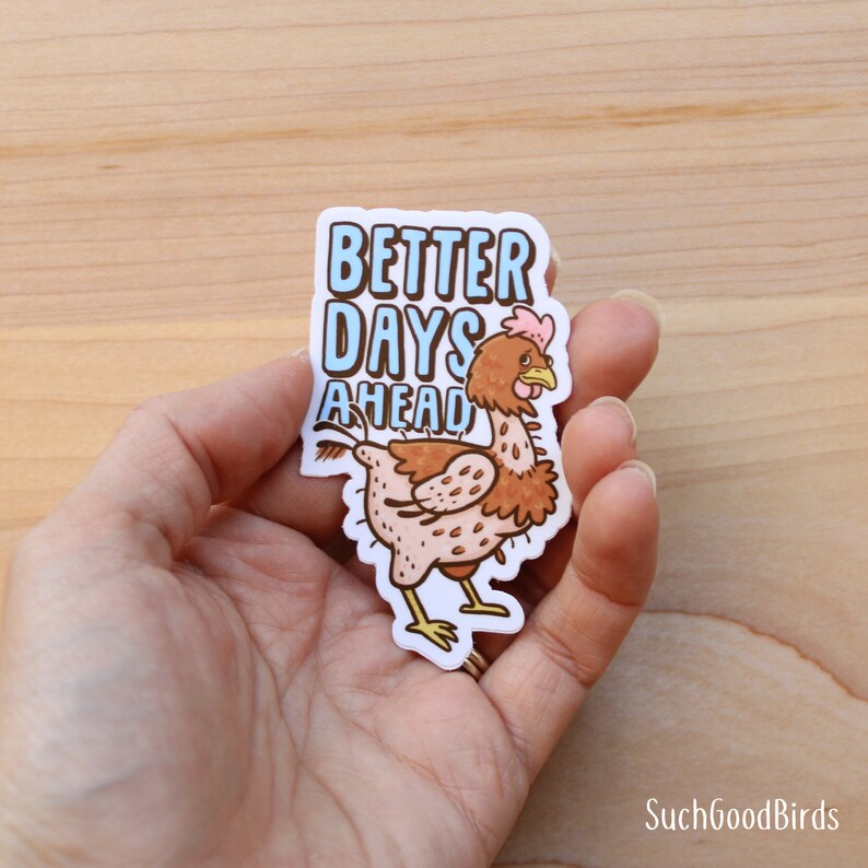 May include: A white sticker with a cartoon chicken with brown feathers and pink wattles. The chicken is walking with its head turned back. The text "Better Days Ahead" is written in blue and white letters above the chicken.