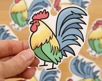 May include: A sticker of a cartoon rooster with a yellow, green, and blue color scheme. The rooster has a red comb and wattle. The rooster is standing on a white background.