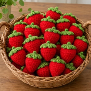 May include: A wicker basket overflowing with handmade crochet strawberries. Each strawberry is a vibrant red with a green leafy top. The basket is filled with many of these charming, decorative items, perfect for home decor or crafting projects.
