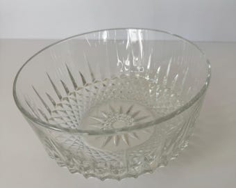 May include: A clear glass bowl with a diamond pattern on the lower half and a starburst design in the center. The bowl has a slanted rim and is suitable for serving salads or fruit.