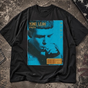 May include: A black short-sleeve t-shirt featuring a large rectangular graphic print of a person in blue tones. The print includes the text YUNG LEAN, Japanese characters, and a barcode with the text KYOTO. The design has a distressed aesthetic.