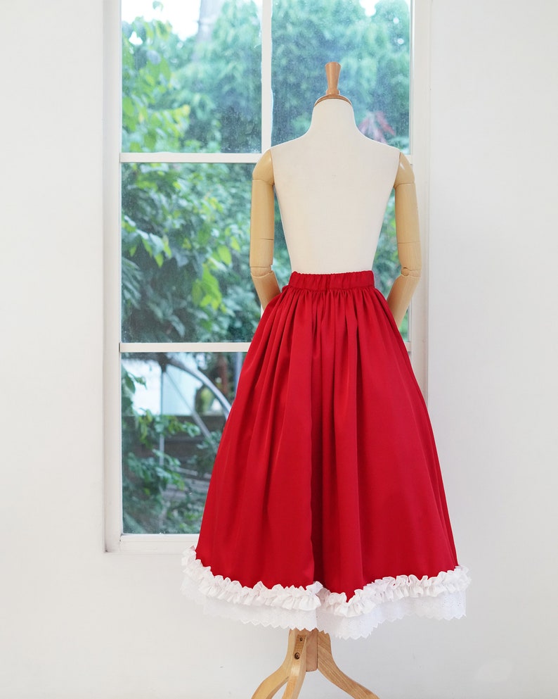 May include: A red skirt with a white lace trim. The skirt is full and has a gathered waist.