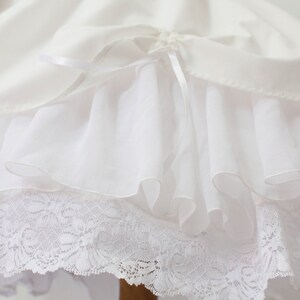 May include: White petticoat with a lace trim and a satin ribbon bow. The petticoat has multiple layers of tulle for volume.