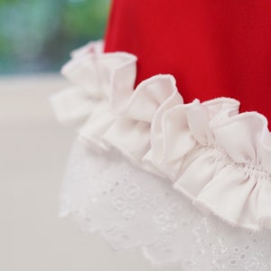 May include: A red dress with a white lace trim and a white ruffle at the bottom.