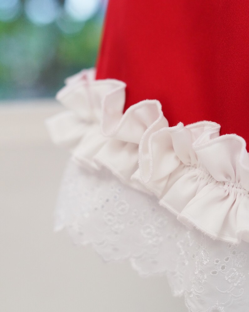 May include: A red dress with a white lace trim and a white ruffle at the bottom.