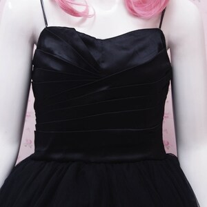 May include: A black satin and tulle dress with a sweetheart neckline and a fitted bodice. The dress has a full skirt and is ideal for a special occasion.