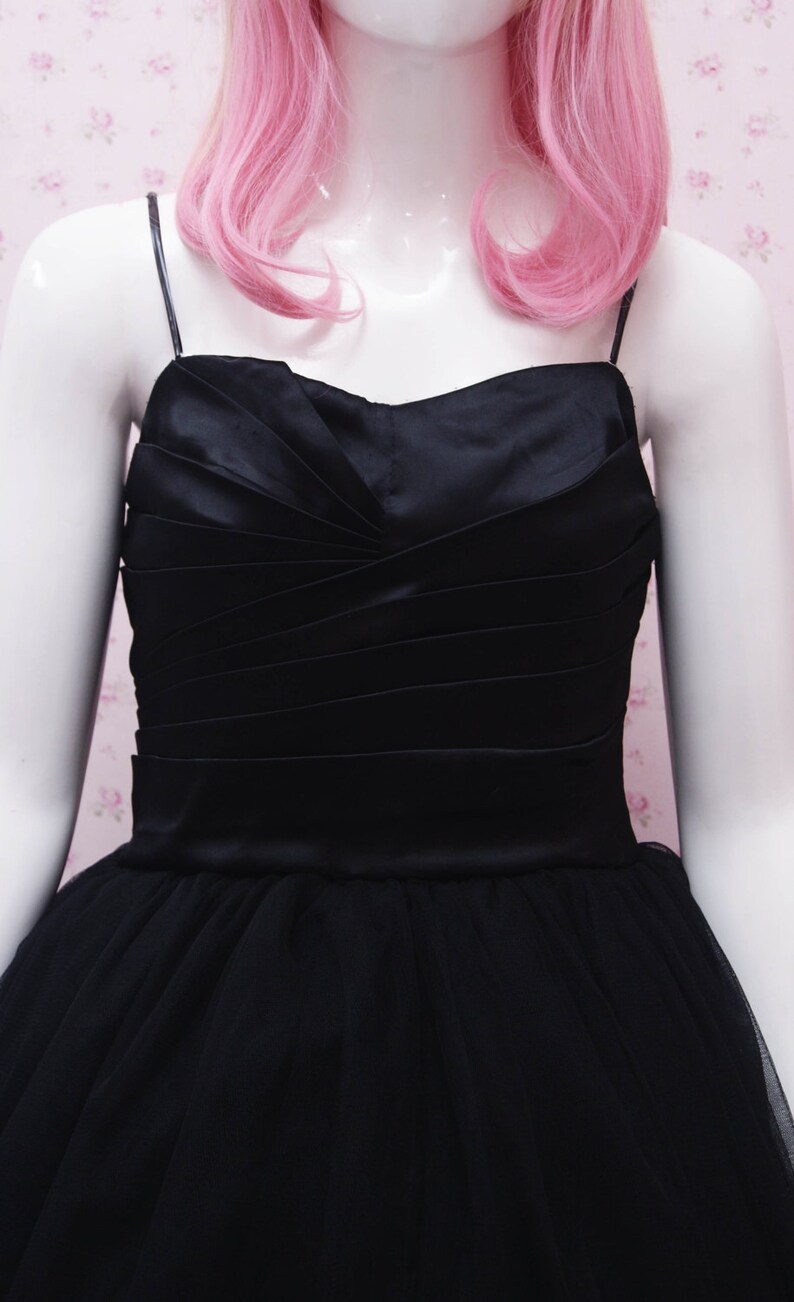 May include: A black satin and tulle dress with a sweetheart neckline and a fitted bodice. The dress has a full skirt and is ideal for a special occasion.