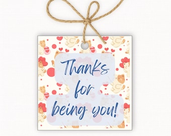 Könnte beinhalten: Quadratisches Geschenk-Etikett mit cremefarbenem Hintergrund mit einem Muster aus Cartoon-Bären und roten Herzen. Das Etikett trägt den Text "Thanks for being you!" in blauer Schrift. Oben ist eine natürliche Bindfaden-Schleife befestigt.