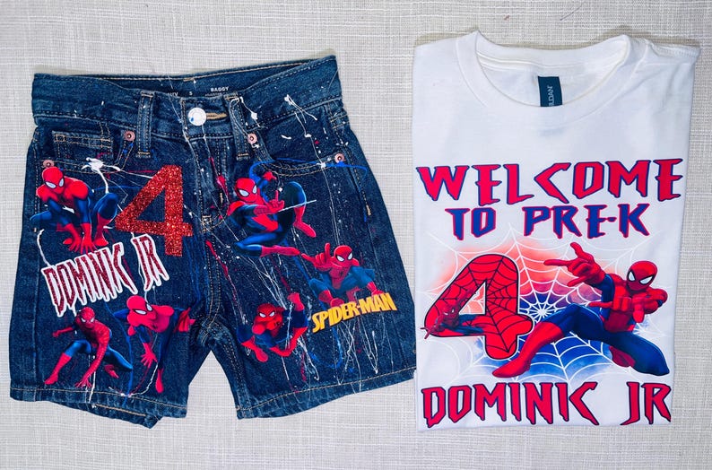 Peut inclure: Un short en jean bleu fonc&eacute; avec des &eacute;claboussures de peinture blanche, un chiffre 4 en paillettes rouges et des motifs Spider-Man, accompagn&eacute; d'un t-shirt blanc avec le texte Welcome to Pre-K, un chiffre 4 rouge, une toile et Spider-Man.