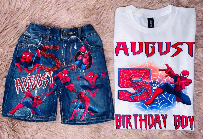 Peut inclure: Un short en jean bleu fonc&eacute; avec le texte rouge paillet&eacute; AUGUST et le chiffre 5, ainsi que plusieurs graphismes de Spider-Man. &Agrave; c&ocirc;t&eacute; se trouve un t-shirt blanc avec le texte AUGUST, 5 et BIRTHDAY BOY, illustr&eacute; avec Spider-Man.