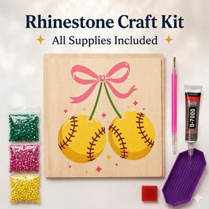 May include: Rhinestone craft kit with all supplies included. The kit features a wooden board with a cherry design, bags of rhinestones, a pink stylus, glue, and a purple tray. The cherry design has yellow softball-like cherries with pink bow.