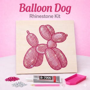 May include: A pink rhinestone kit featuring a balloon dog design on a wooden board. The kit includes rhinestones, glue, a stylus, and a tray. The text "Balloon Dog Rhinestone Kit" is displayed at the top.