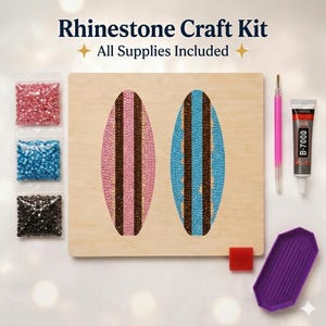 May include: Rhinestone craft kit with all supplies included. The kit features a wooden board with two oval designs, one pink and one blue, decorated with rhinestones. Additional supplies include bags of rhinestones, a pink stylus, glue, and a purple tray.