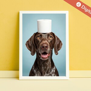 May include: A framed print featuring a brown dog with a white roll of toilet paper balanced on its head. The dog has brown eyes and a happy expression. The background is a light blue, and the frame is white.