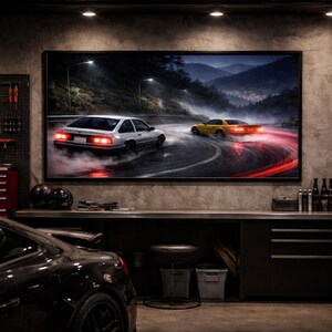 May include: A framed artwork depicting two sports cars drifting on a winding road at night. The cars are white and yellow, with red taillights and tire smoke. The scene is set in a garage with tools, tires, and a black car in the foreground.