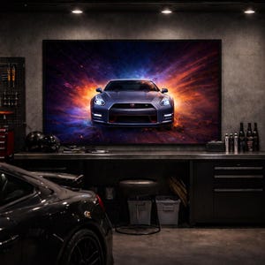 May include: A dark garage setting with a large framed image of a blue sports car. The car is centered, with bright headlights and a red accent. Tools and equipment are visible, along with a black sports car in the foreground.