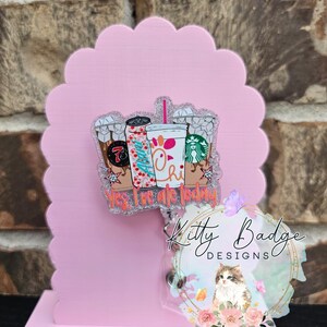 May include: A glittery acrylic badge reel featuring a graphic of three beverage cups and the text Yes, I've ate today. The design includes a 7-Eleven cup, a soda can with the name Allan, and a Chick-fil-A cup with a Starbucks logo nearby.