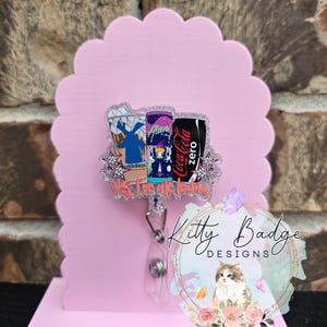 May include: An acrylic badge reel featuring a glittery design of three beverage containers, including a Dutch Bros cup, an Alani Nu can, and a Coca-Cola Zero can, with the text "Yes, I've ate today" printed in orange below the drinks.