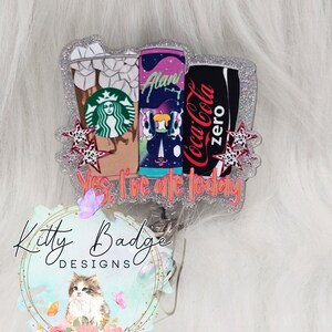 May include: A glittery badge reel featuring a Starbucks iced coffee cup, an Alani energy drink can, and a Coca-Cola Zero can. The design includes small star accents and the text Yes, I've ate today in orange lettering. The badge has a silver glitter border.
