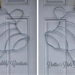 May include: Two silver metal wire wreath forms shaped like a fish. The forms are hanging on a white door. The text "Dottie Dots Bubbly Creations" is printed below each form.