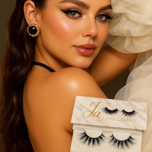 May include: A woman with dramatic eye makeup and long eyelashes. The image features a package of "Diva" false eyelashes from "Ja Lexa Lashes". The packaging is white with a marble design and gold lettering.