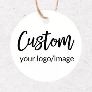 Könnte beinhalten: Ein weißes, rundes Etikett mit dem Wort "Custom" in schwarzer Schrift. Darunter steht der Text "your logo/image" in einer kleineren Schriftart ohne Serifen. Oben ist eine natürliche Schnur befestigt.