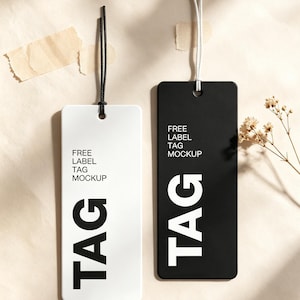 Könnte beinhalten: Zwei rechteckige Anhänger, einer weiß mit schwarzem Text und einer schwarz mit weißem Text. Beide Anhänger tragen die aufgedruckten Wörter FREE LABEL TAG MOCKUP und das Wort TAG in großen Buchstaben. Jeder Anhänger hat eine Schnurschlaufe oben.