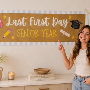 Può includere: Uno striscione rettangolare con bordo a righe azzurre e bianche e sfondo dorato. Il testo recita Last First Day SENIOR YEAR in bianco e giallo. Le illustrazioni includono un quaderno rosa, una matita gialla, un diploma e un tocco.