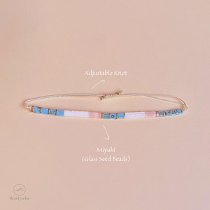 May include: A necklace with an adjustable knot, made with Miyuki glass seed beads. The beads are white, pink, and turquoise. The text "Adjustable Knot" and "Miyuki (Glass Seed Beads)" are visible.