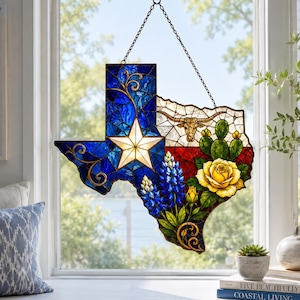 May include: A stained glass suncatcher shaped like the state of Texas, featuring a blue section with a white star, a red section, and a white section. It includes a longhorn skull, bluebonnet flowers, and a yellow rose, all suspended by a chain.
