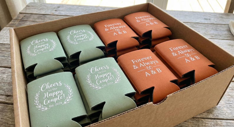 Bulk custom wedding can coolers packed and ready to ship, featuring sage green and terracotta neoprene sleeves with cheers to the happy couple and forever and always messages. Perfect for fall weddings, outdoor receptions, and rustic venues. Made to order with crisp professional printing for consistent results. These reusable drink sleeves simplify event planning while offering guests a practical favor they can enjoy long after the wedding day has passed.